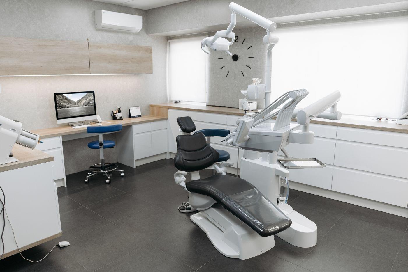 A bright dental treatment room with a chair and examination equipment